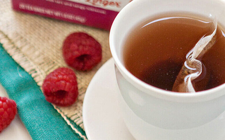 teacup with tea in it, next to some raspberries