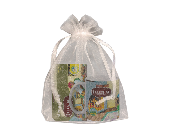 A sheer white organza bag containing a colorful mug and a box of Celestial tea. The set is elegantly tied with a satin ribbon.