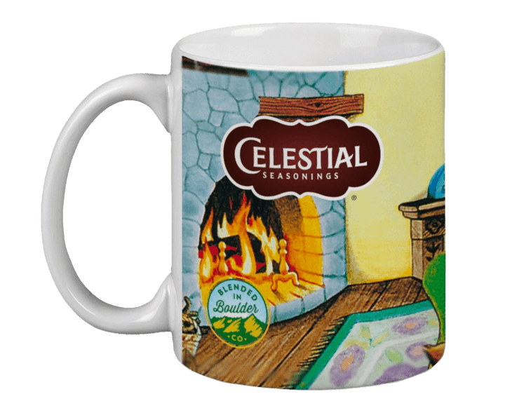 Ceramic mug featuring a cozy fireplace illustration with a warm flame, "Celestial Seasonings" logo, and "Blended in Boulder, CO" emblem, evoking warmth.